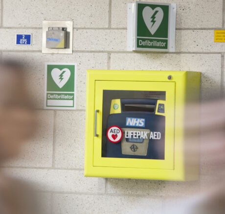 A Defibrillator attached to a wall in a yellow cabinet