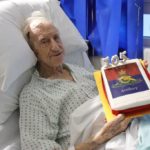 George on a hospital bed holding his cake