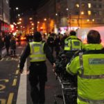 Ambulance service medics with a trolley bed making there way through a busy city centre street