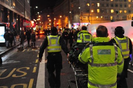 Ambulance service medics with a trolley bed making there way through a busy city centre street