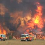 Australian bushfires raging and two fire engines in foreground