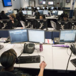 row of desks and computer screens in control room