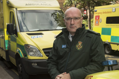 Garrett Emmerson stood in a green Service jacket in front of an ambulance