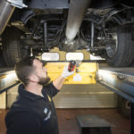 Workshop staff member looks beneath ambulance on ramp