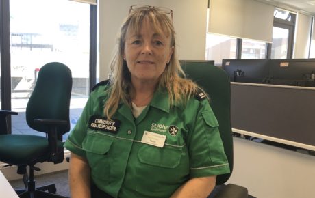 Fiona, in green St John Ambulance uniform sat at a desk