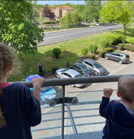 Andrew waves to his children as they stand on their balcony