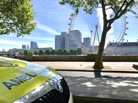 ambulance car parked with London Eye and blue skies in background