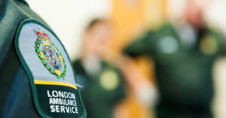 The London Ambulance logo on the green uniform