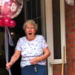 Mike's grandmother holding balloon looking happy and surprised