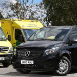 Black Mercendes van next to two ambulances