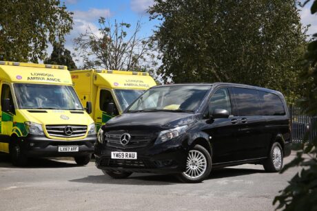 A black mercedes van parked in front of two ambulances