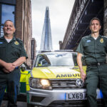 Gary and Fabio stood in front of an ambulance car with The Shard in background