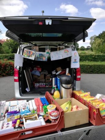 A van with rear boot open and a table of drinks and snacks