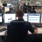 Peter shown from behind at his desk with multiple computer screens