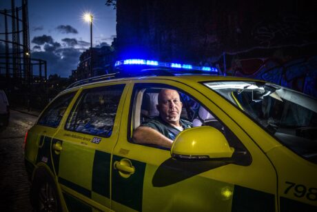 Pete sat in an ambulance car with its blue lights flashing