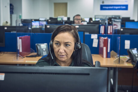 111 call handler with headset sat at computer