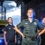 Stuart, Rachel and Pete stood in front on an ambulance in a dark setting