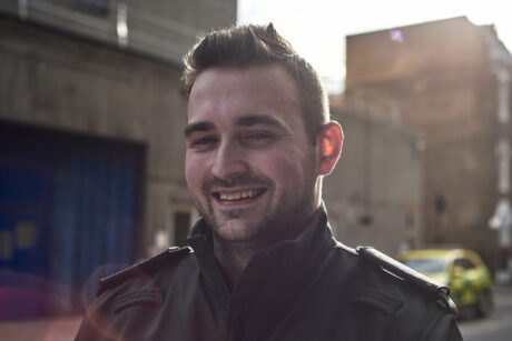 Kieran smiling with an ambulance car in the background