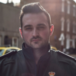 Kieran in uniform with ambulance vehicles in background