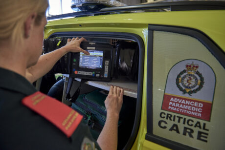 Advanced paramedic operating some equipment in rear of ambulance car