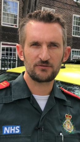 Advanced paramedic Kevin in uniform with ambulance car in background