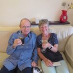 Brian and Sally sat on a sofa raising a glass eacg