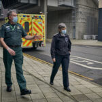 Met Commissioner walking alongside LAS staff member with an ambulance in background