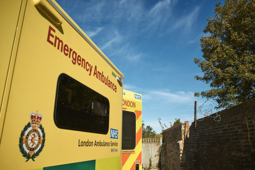 The side of an ambulance with back doors open and blue sky
