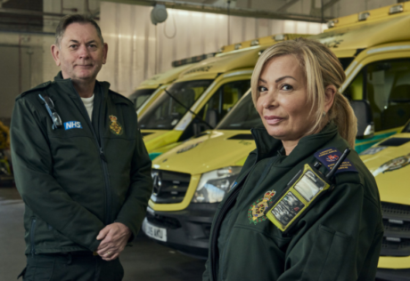 Dave and Ellie stood in LAS uniform in front of a row of ambulances
