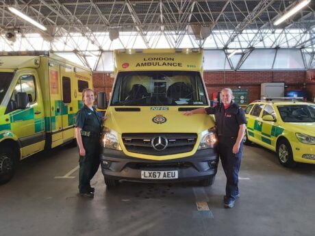 Samantha and Sheila stood in their different uniforms either side of an ambulance bonnet