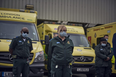 Uniformed LAS staff in front of ambulances observing the minute silence