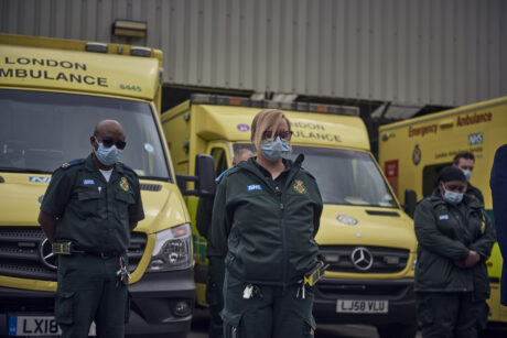 Uniformed LAS staff in front of ambulances observing the minute silence