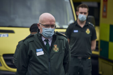 Uniformed LAS staff in front of ambulances observing the minute silence