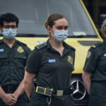 Uniformed LAS staff in front of ambulances observing the minute silence
