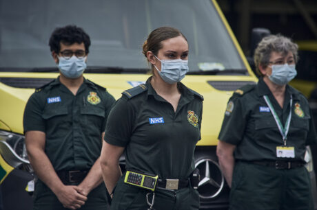 Uniformed LAS staff in front of ambulances observing the minute silence