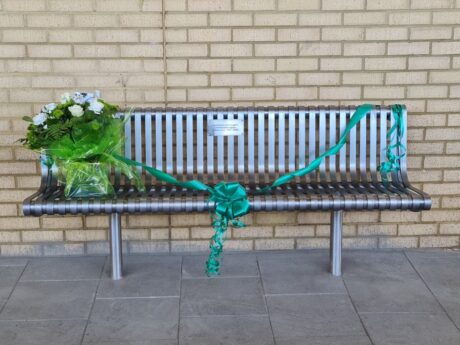 The memorial bench with a bouquet of flowers