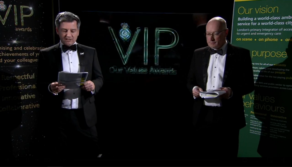 The presenters in suits ahead of a screen which reads VIP Awards