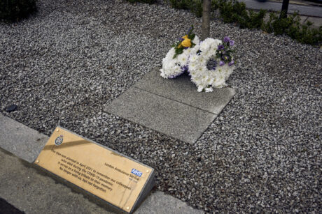 A flower wreath at the foot of the memorial tree and an engraved plaque