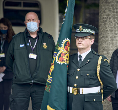 A member of the ceremonial unit holding the Service commemorative flag