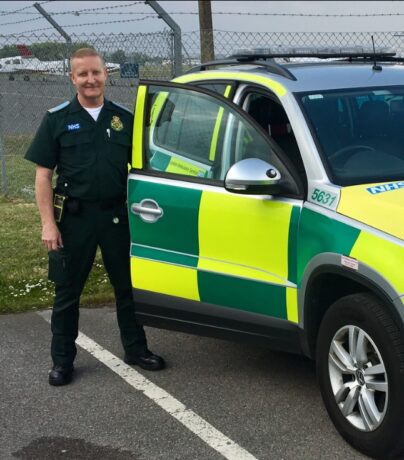 Tony in LAS uniform next to an ambulance car