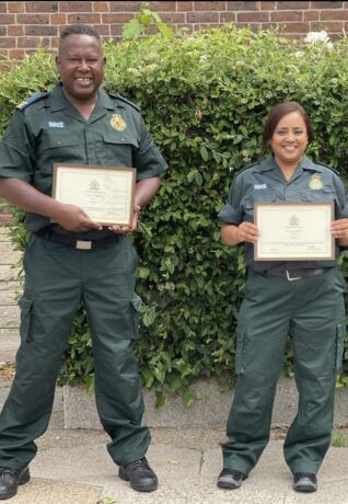 Keith and Sukhjit in uniform photographed smiling holding their certificates