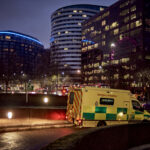 An ambulance leaving a hospital ramp at night