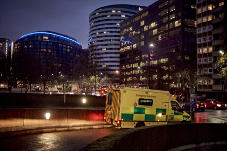 An ambulance leaving a hospital ramp at night
