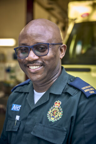 Femi photographed smiling in his Service uniform in front of an ambulance