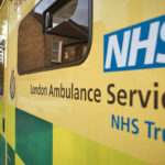 Stock image of the side of an ambulance with the NHS logo visible and the words London Ambulance Service NHS Trust