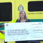 André holds a large novelty cheque with the amount raised with a represenative from the RBL alongside LAS Chief Executive Daniel Elkeles