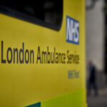 The side of an ambulance and the NHS logo and words London Ambulance Service visible
