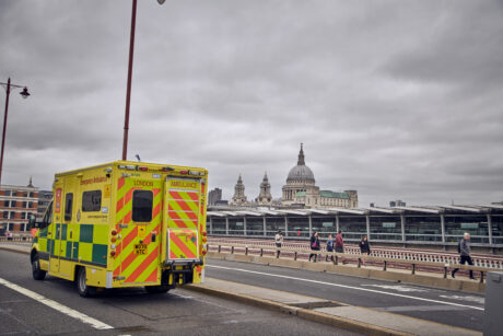 An ambulance passes over Blackfriars Bridge with the City skyline and St Paul's Cathedral in background