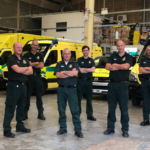 Stuart and his colleagues stood in a group in an ambulance base for a group photograph