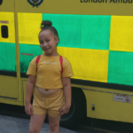 Ariana smiling photographed stood in front of an ambulance